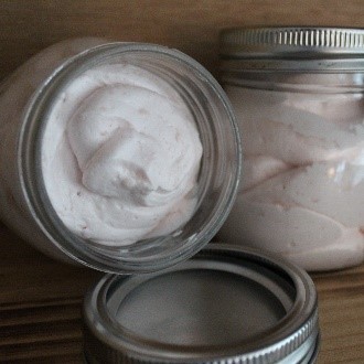 A jar of body butter sitting on top of a wooden shelf.