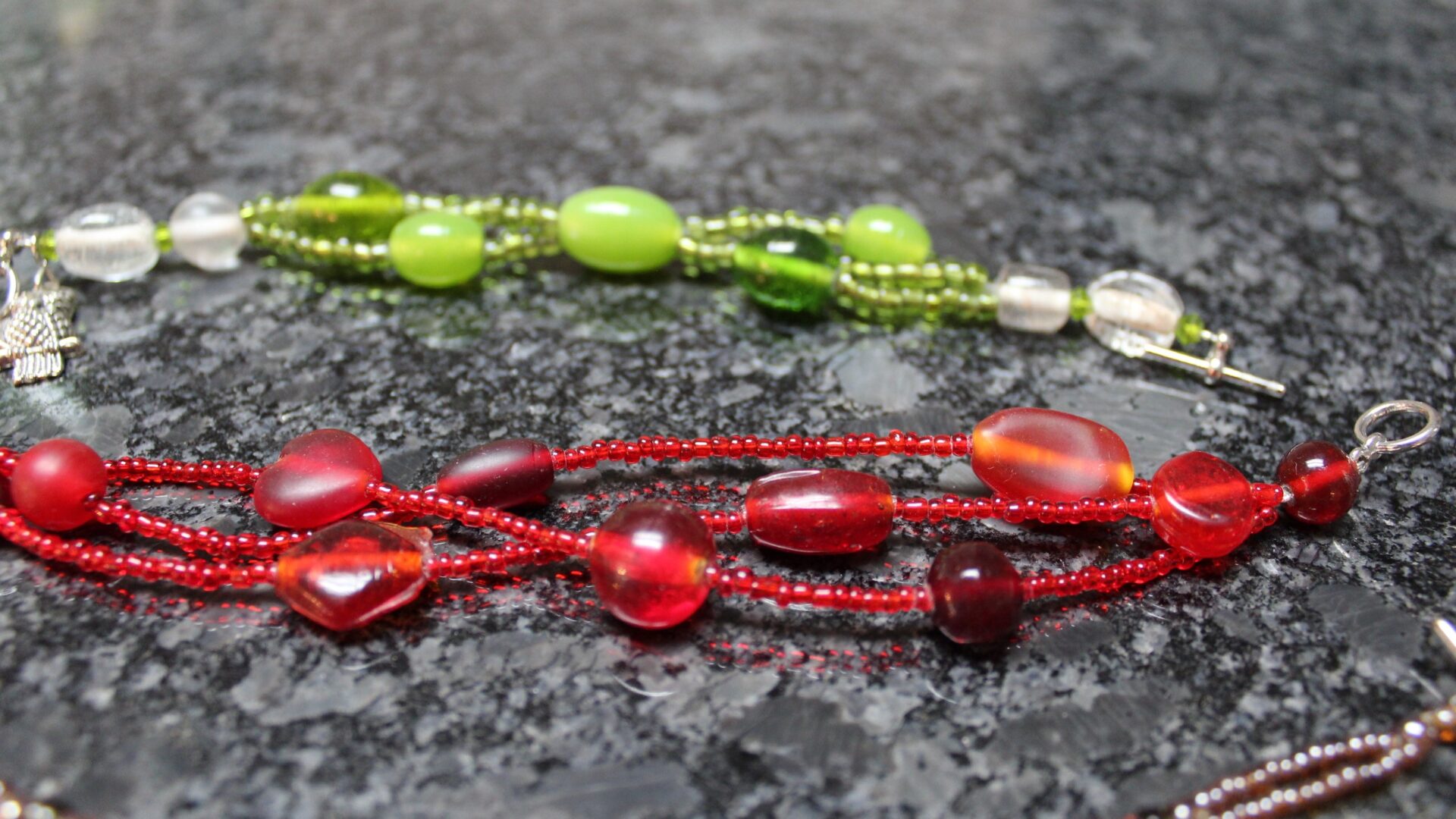 Two necklaces of different colors are shown on a table.