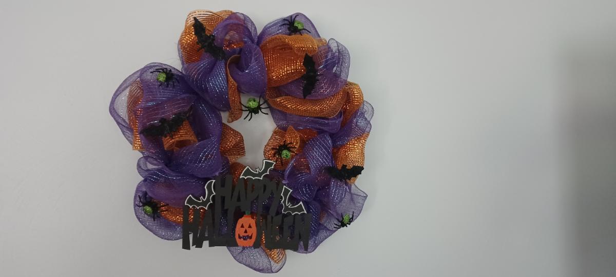 A purple and orange wreath with spiders on it.