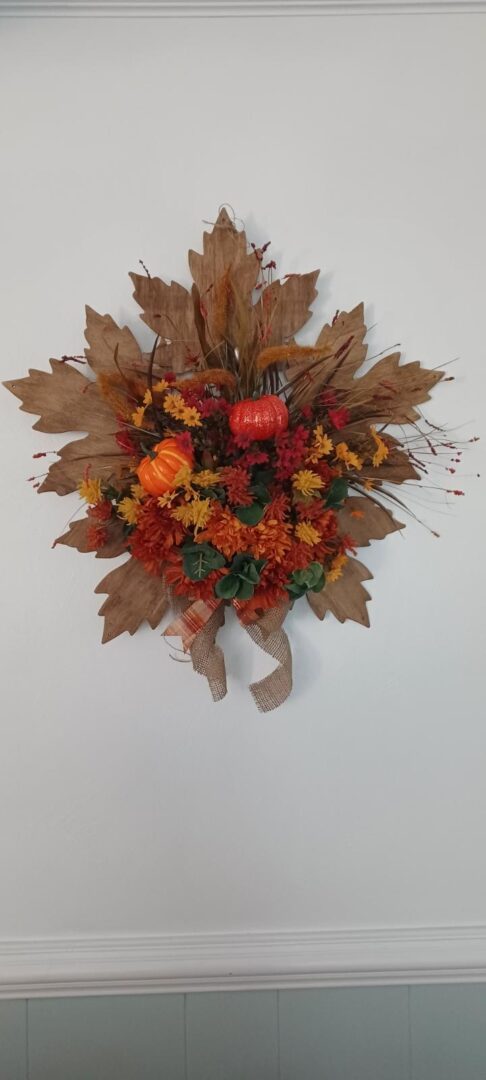 A wreath of leaves and flowers hanging on the wall.