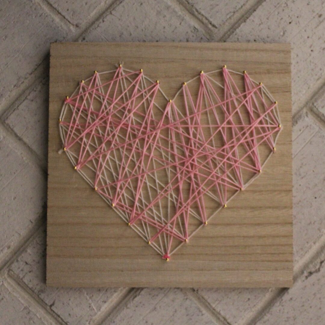 A wooden board with string art on it