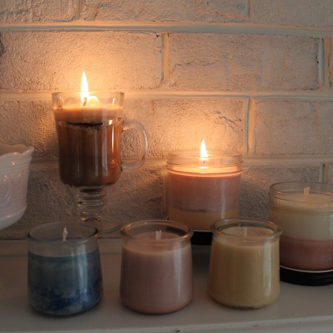 Candles are lit on a mantle in front of brick wall.