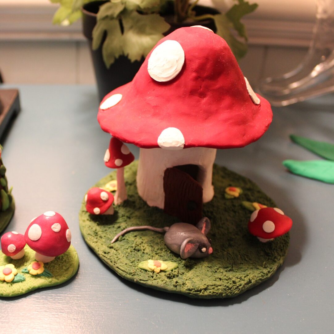 A mushroom house with a mouse on the ground