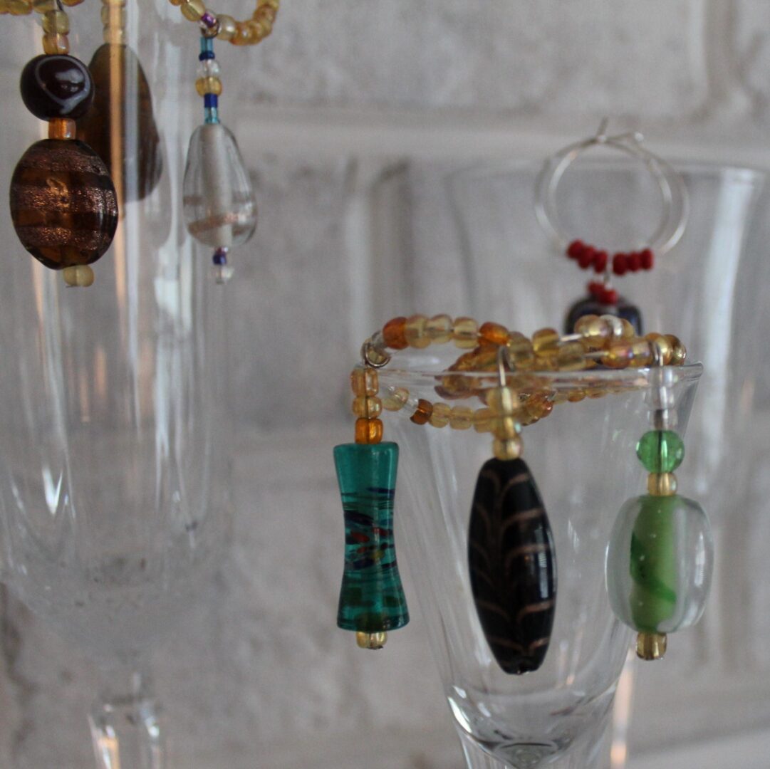 A close up of some wine glasses with different types of beads hanging from them.