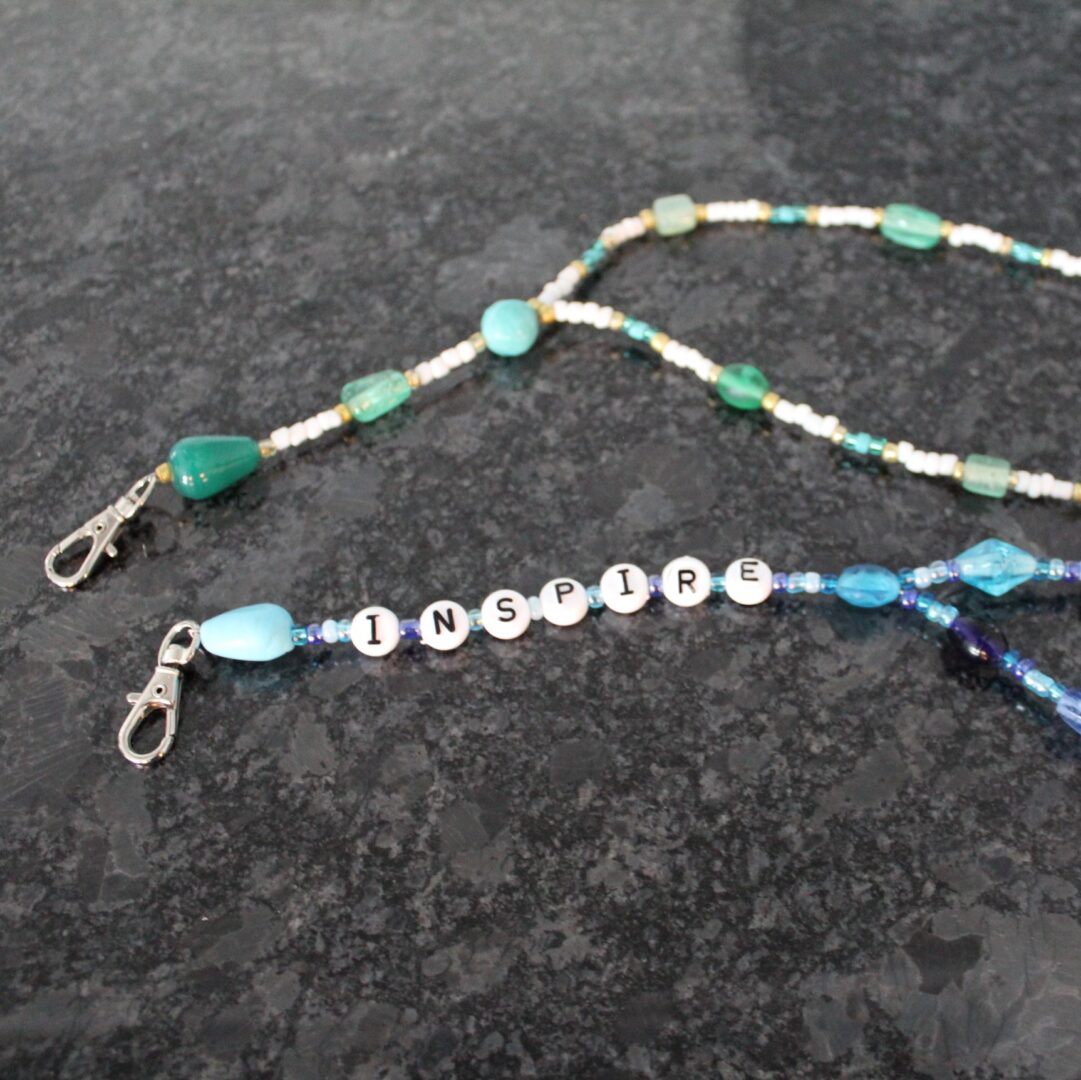 A pair of beaded glasses chains with blue and green beads.