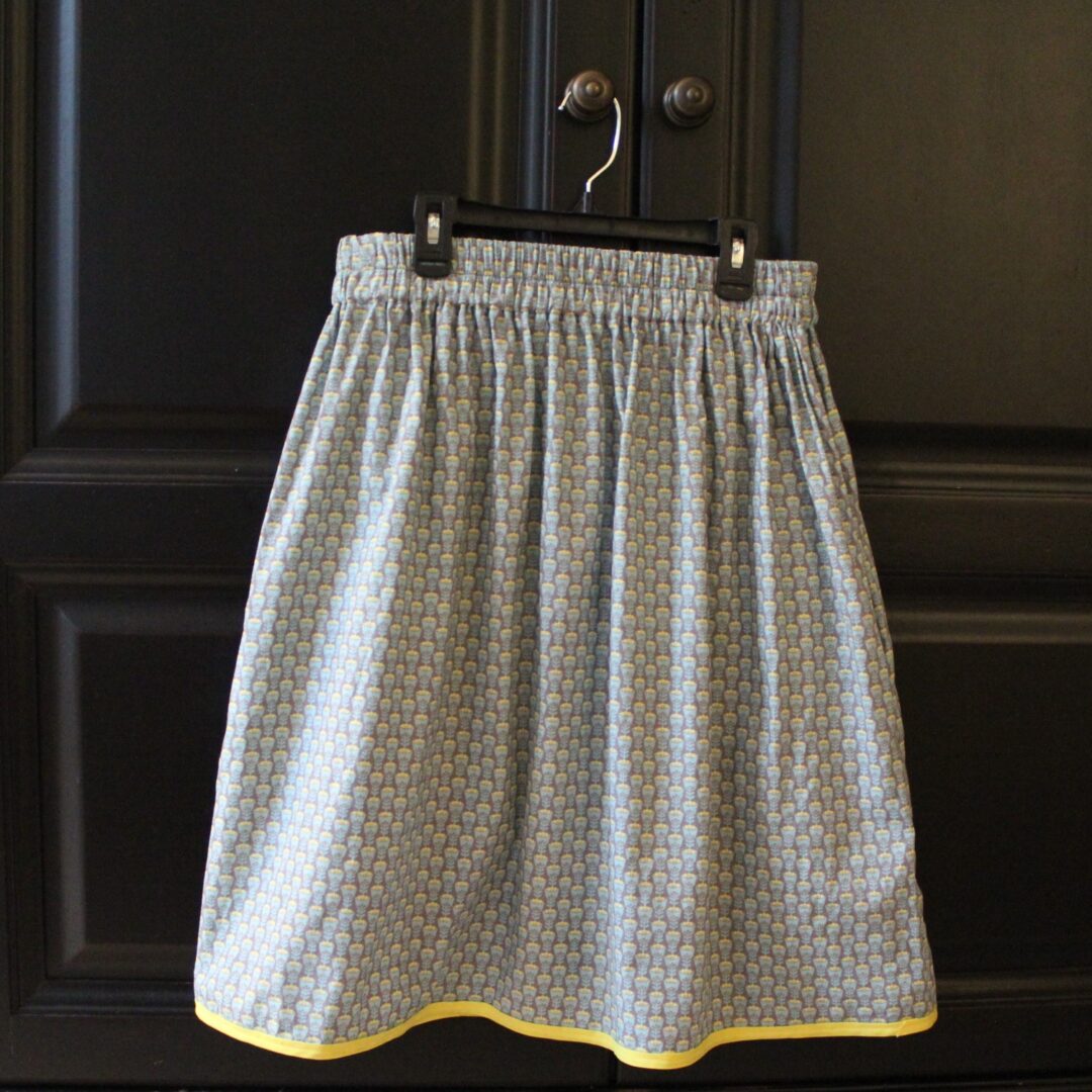 A skirt hanging on the wall with two yellow trim.