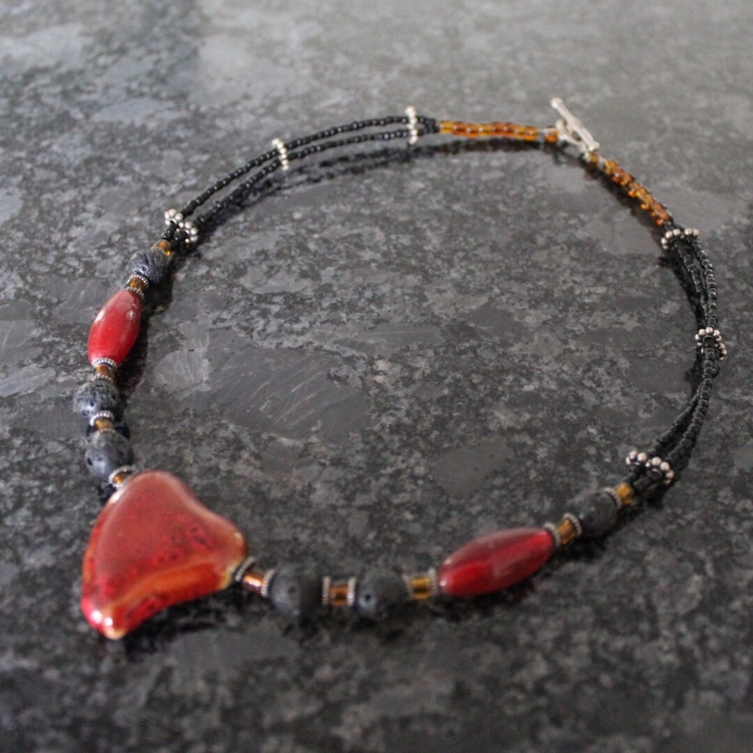 A necklace with red and black beads on it.