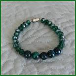 A green bracelet is sitting on the bed.