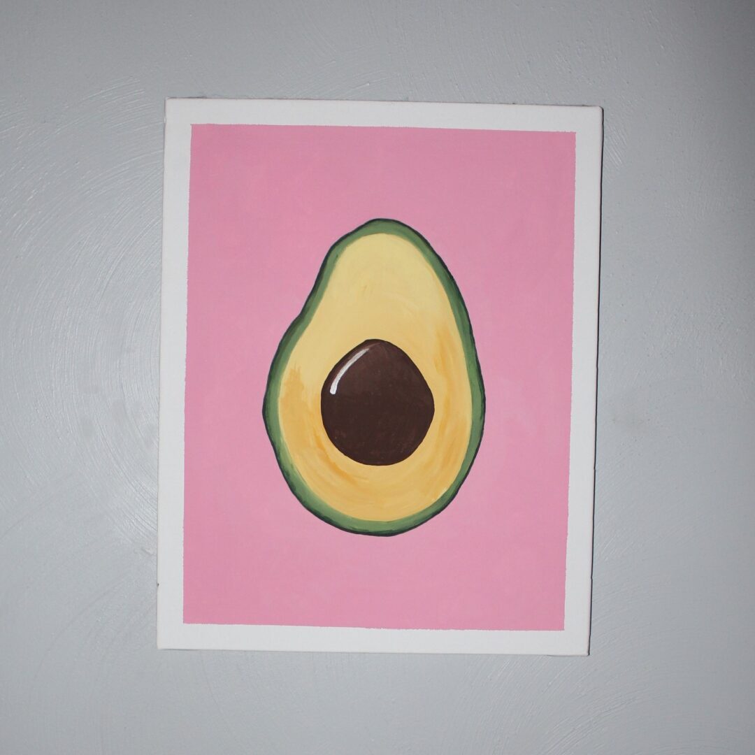 A pink and green avocado on top of a white wall.